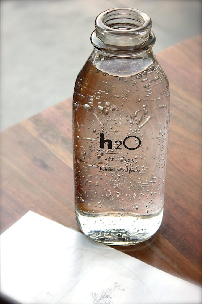 clear-glass-h2o-bottle-on-woodgrain-table