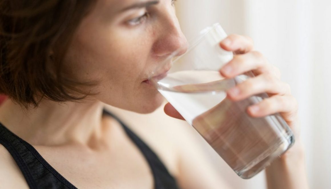 woman-in-black-tank-top-drinking-water-PcU17evKnew