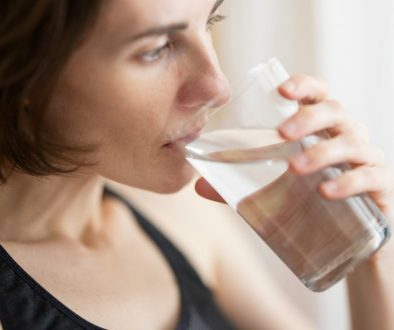 woman-in-black-tank-top-drinking-water-PcU17evKnew
