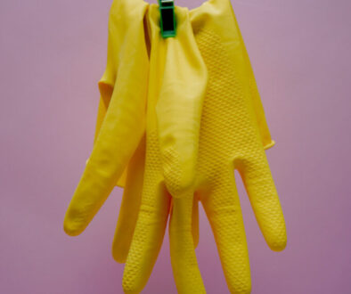 Yellow cleaning gloves hanging from a string.karolina-kolodziejczak