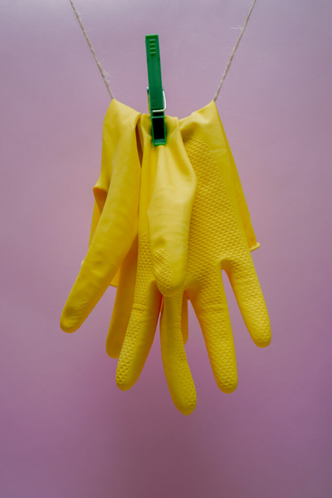 Yellow cleaning gloves hanging from a string.karolina-kolodziejczak